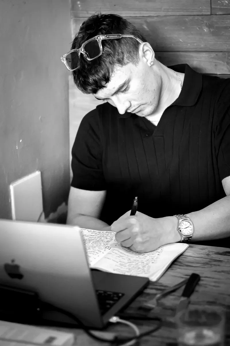 A content plan for a month of real estate videos, written by hand beside a laptop